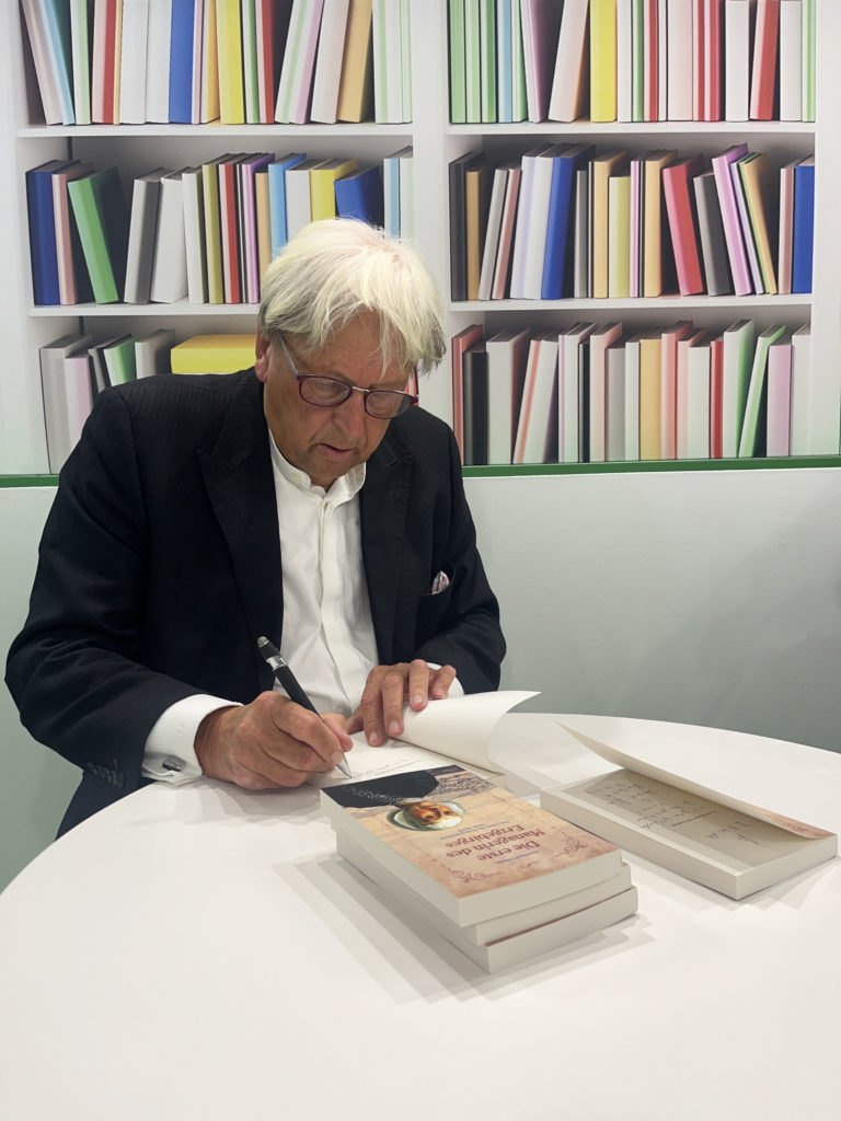 Ein Bild von Eberhard Görner beim Signieren seiner Bücher.